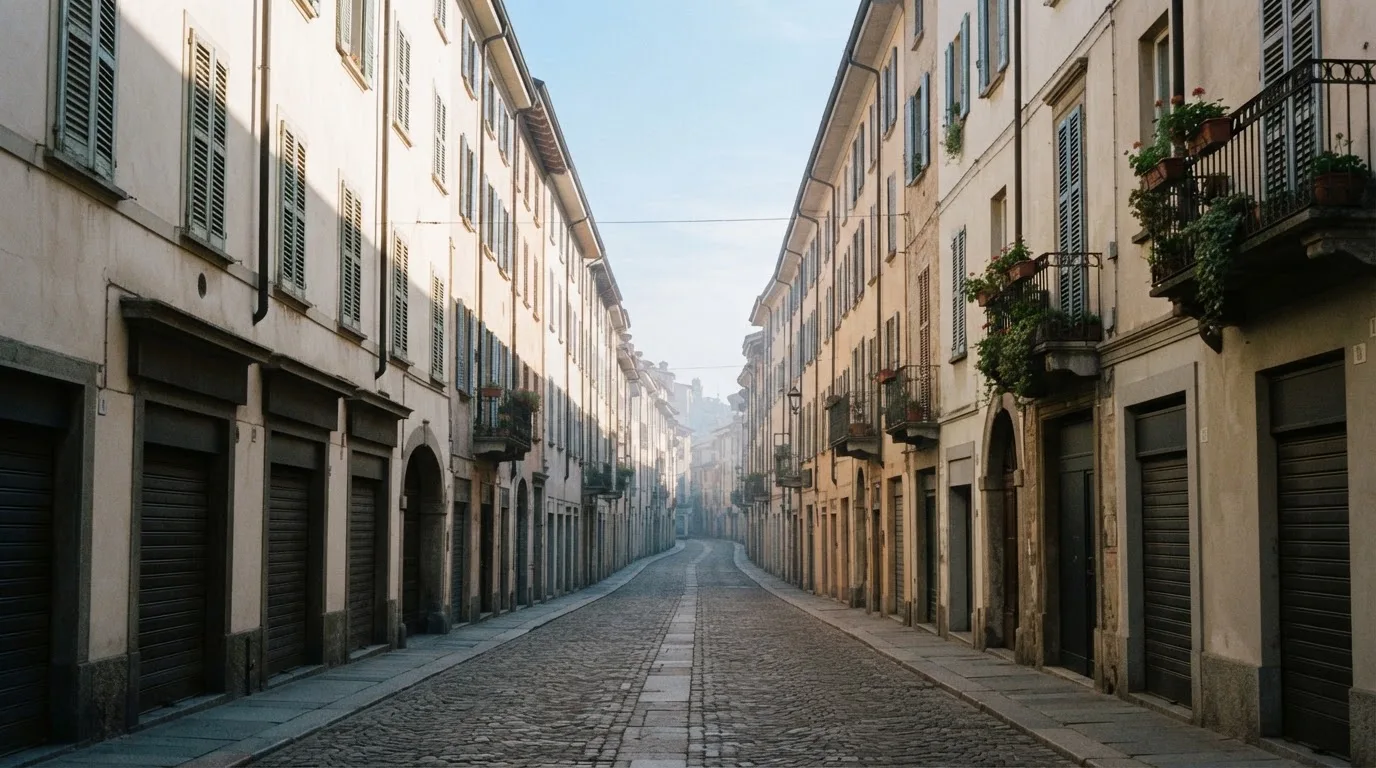 Ein ruhiger Straßenzug in einer Altstadt am Vormittag, helle Fassaden, keine Schilder, niemand ist zu sehen.