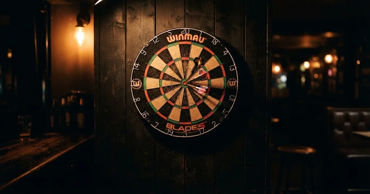 Eine Dartscheibe an einer Holzwand in einem schwach beleuchteten Raum, drei Pfeile stecken nahe der Mitte, warmes Licht von der Seite.